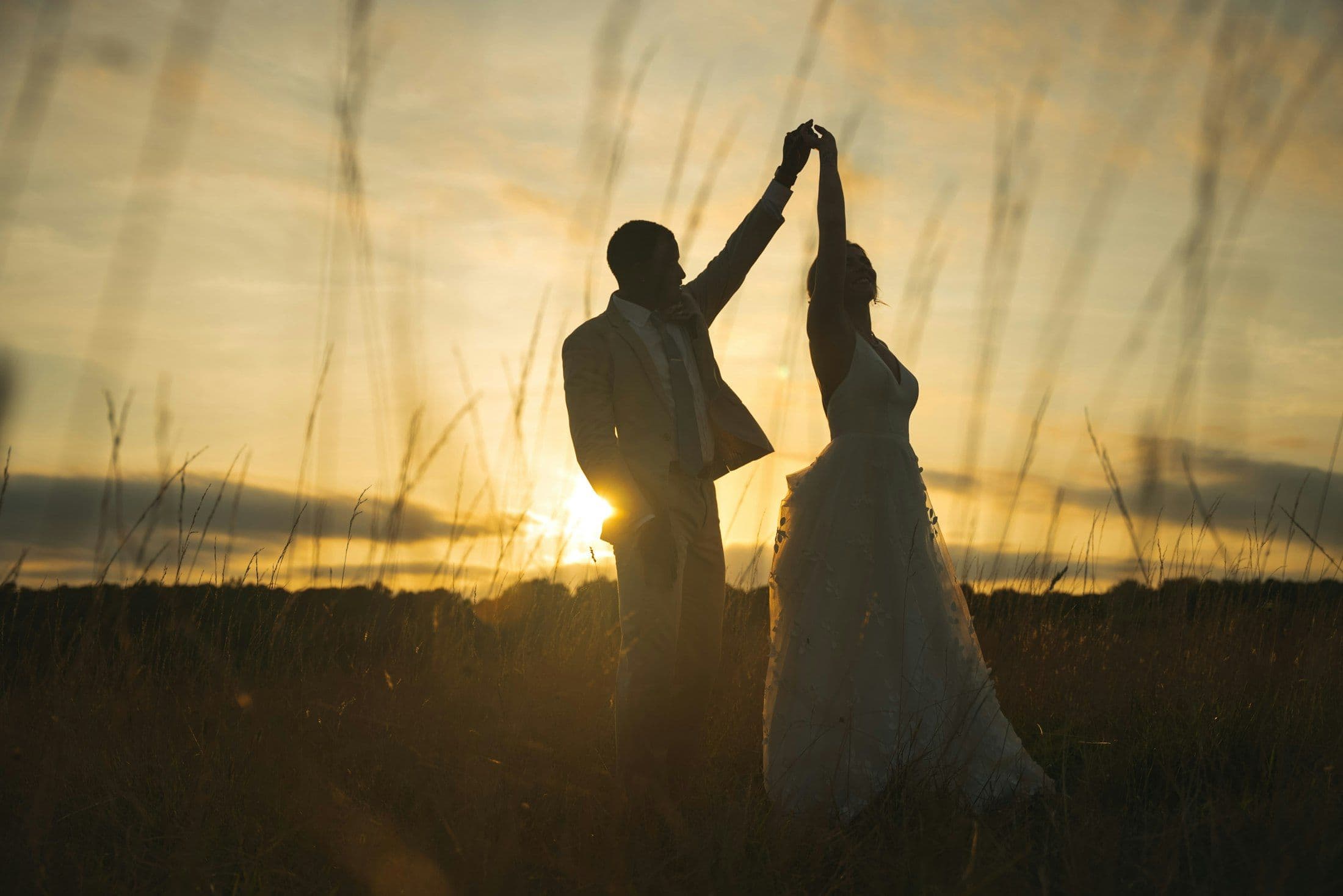 A couple dancing in a vineyard as the sun sets